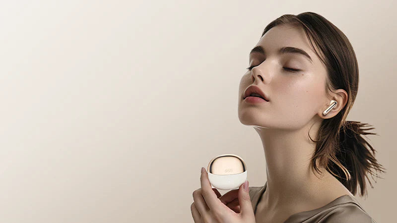Frau mit geschlossenen Augen hält Premium-Ohrhörer und Ladecase – stilvolles Design für hochwertigen Klanggenuss.