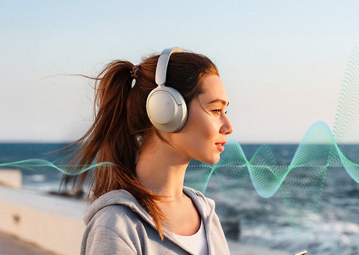 Mujer con auriculares inalámbricos en el mar, escuchando música
