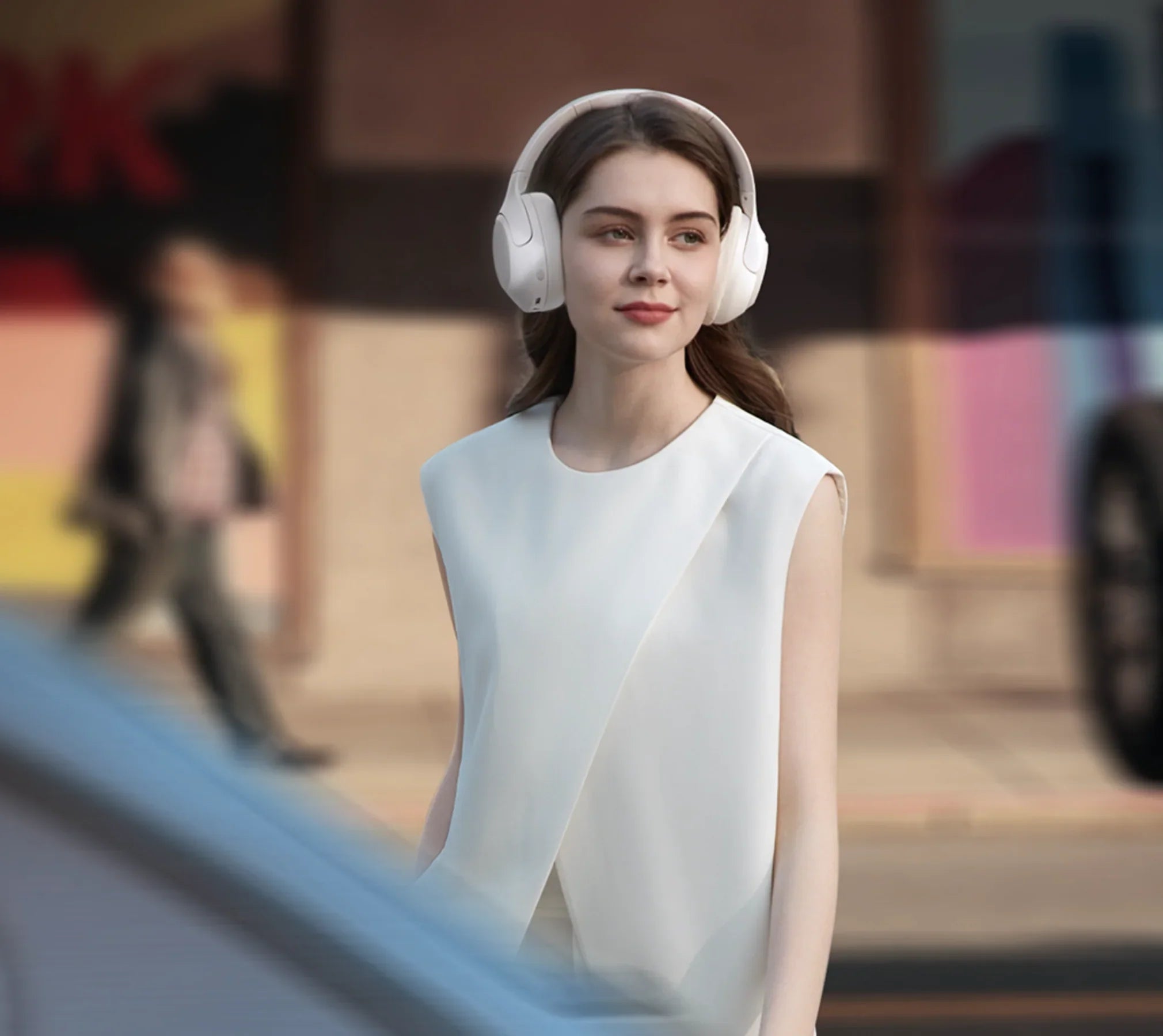 Mujer con auriculares blancos Over-Ear en un entorno urbano, moda elegante, tecnología moderna
