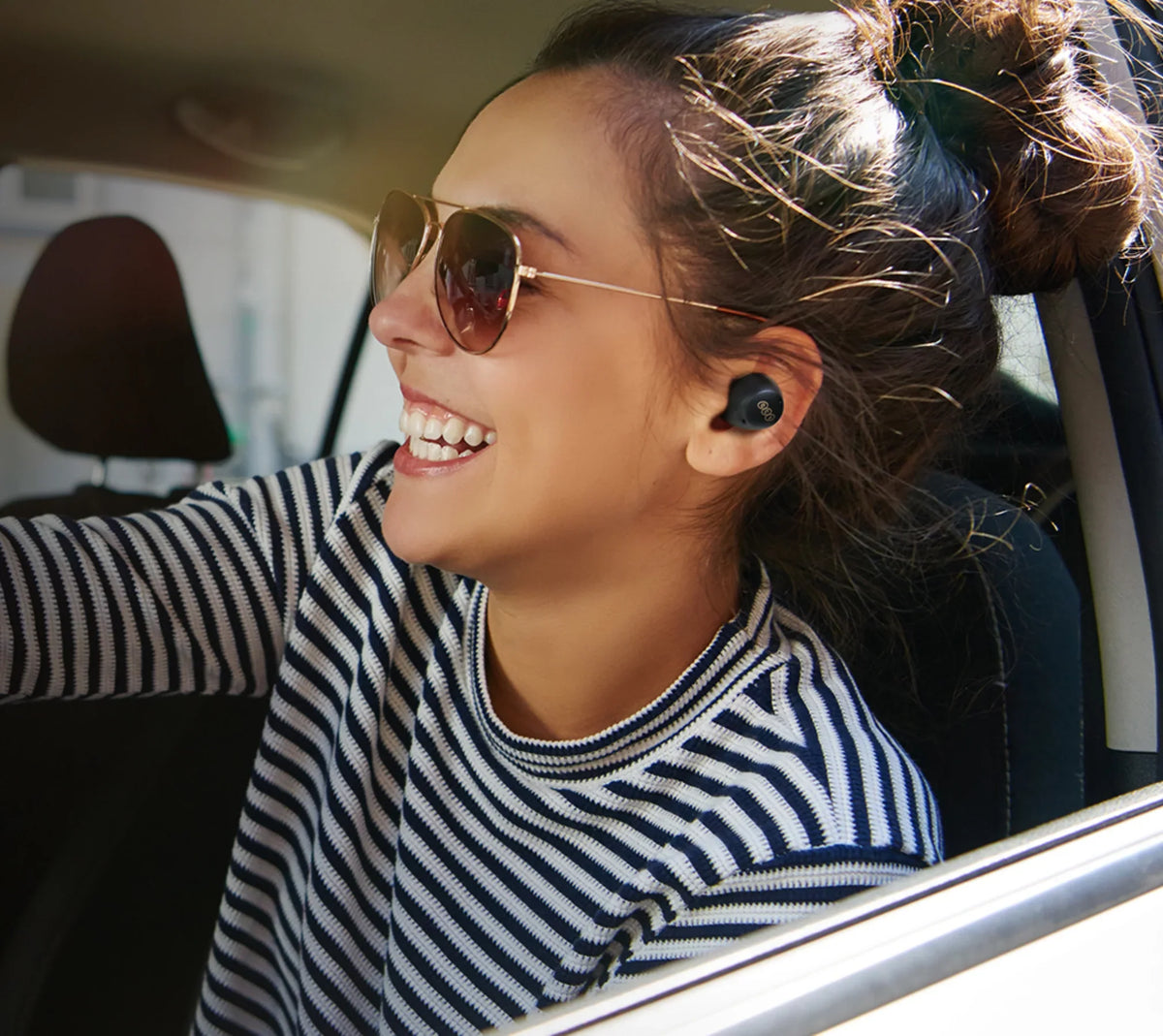 Mujer con gafas de sol y auriculares inalámbricos en el coche