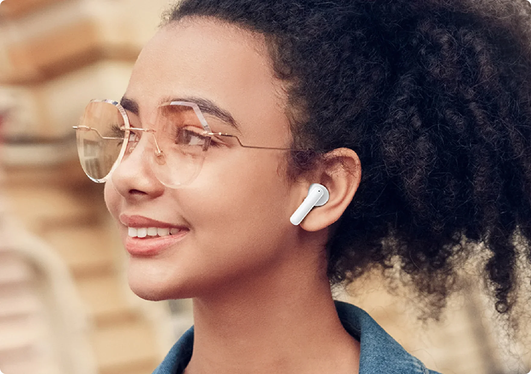 Mujer de perfil con auriculares inalámbricos blancos y gafas de sol.
