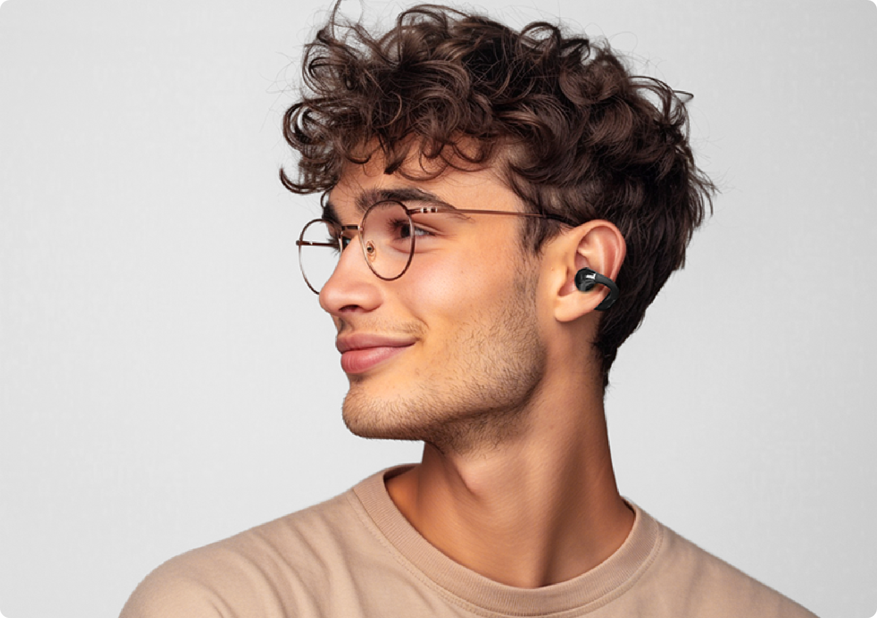Joven con gafas y auriculares inalámbricos de perfil.