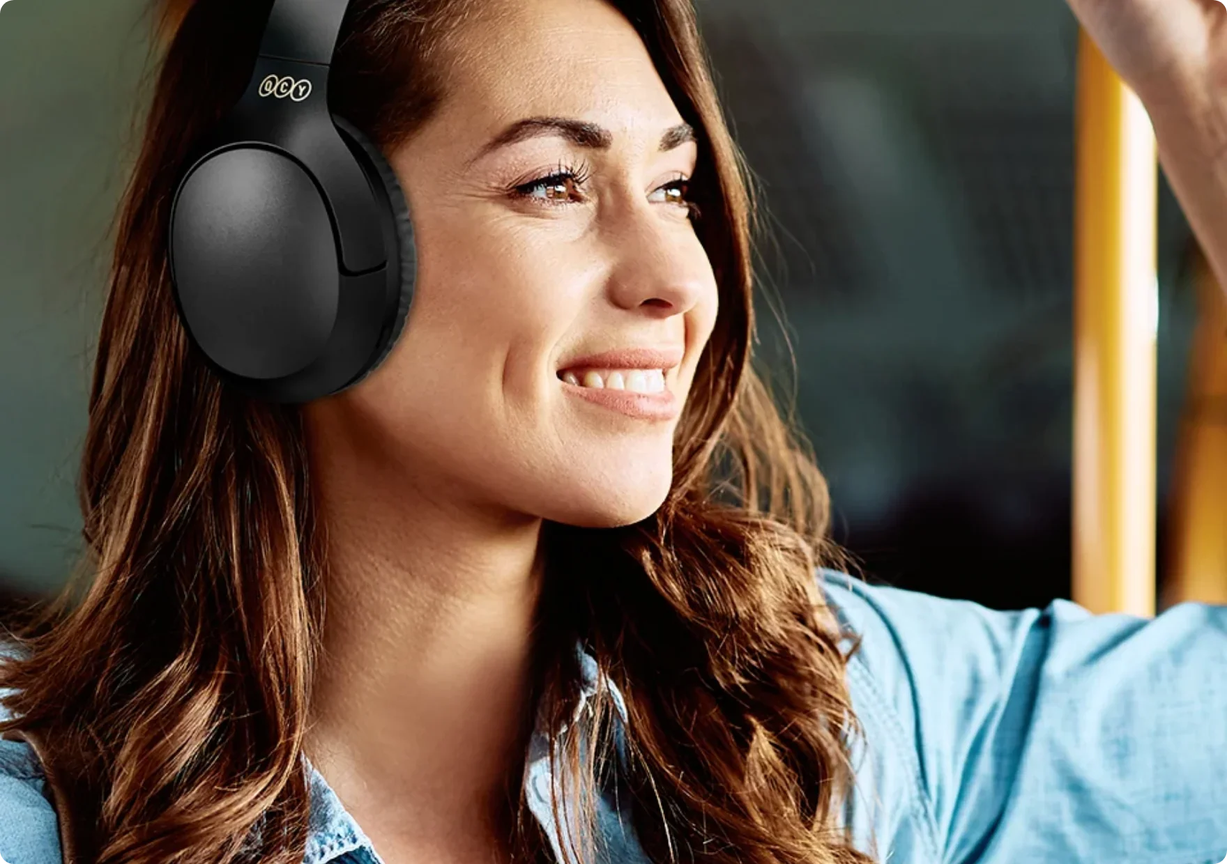 Mujer con auriculares negros Over-Ear sonriendo en el autobús.