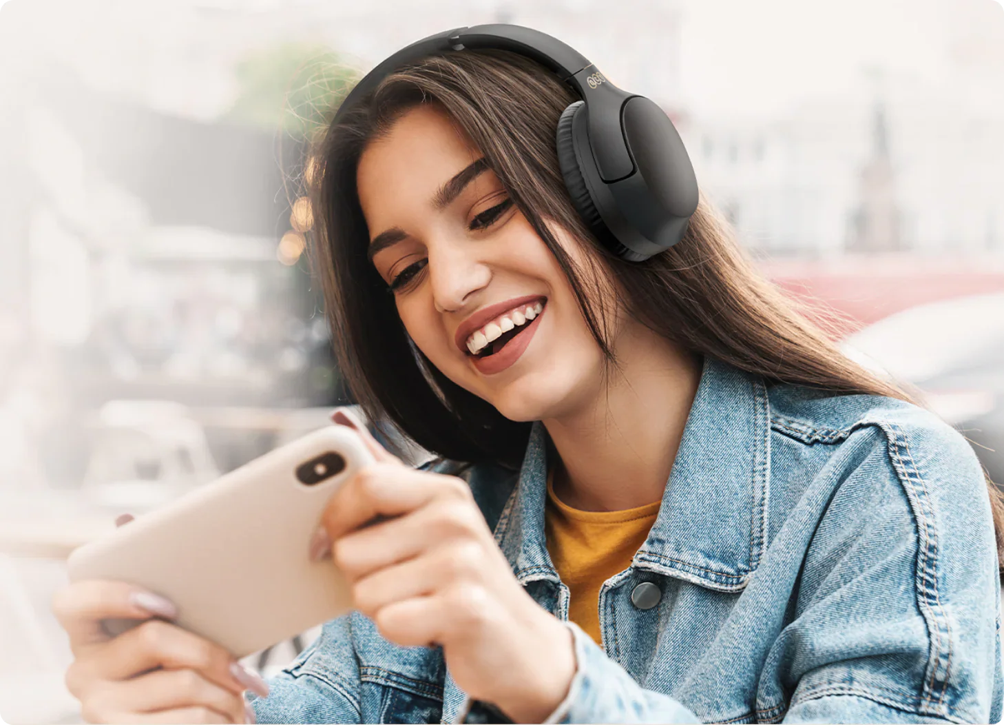 Mujer sonriente con auriculares inalámbricos y smartphone.