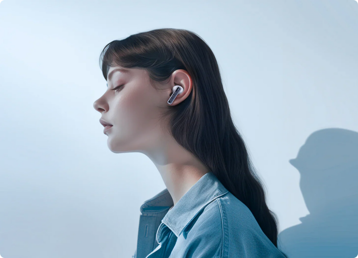 Mujer con auriculares Bluetooth blancos y chaqueta vaquera, vista lateral