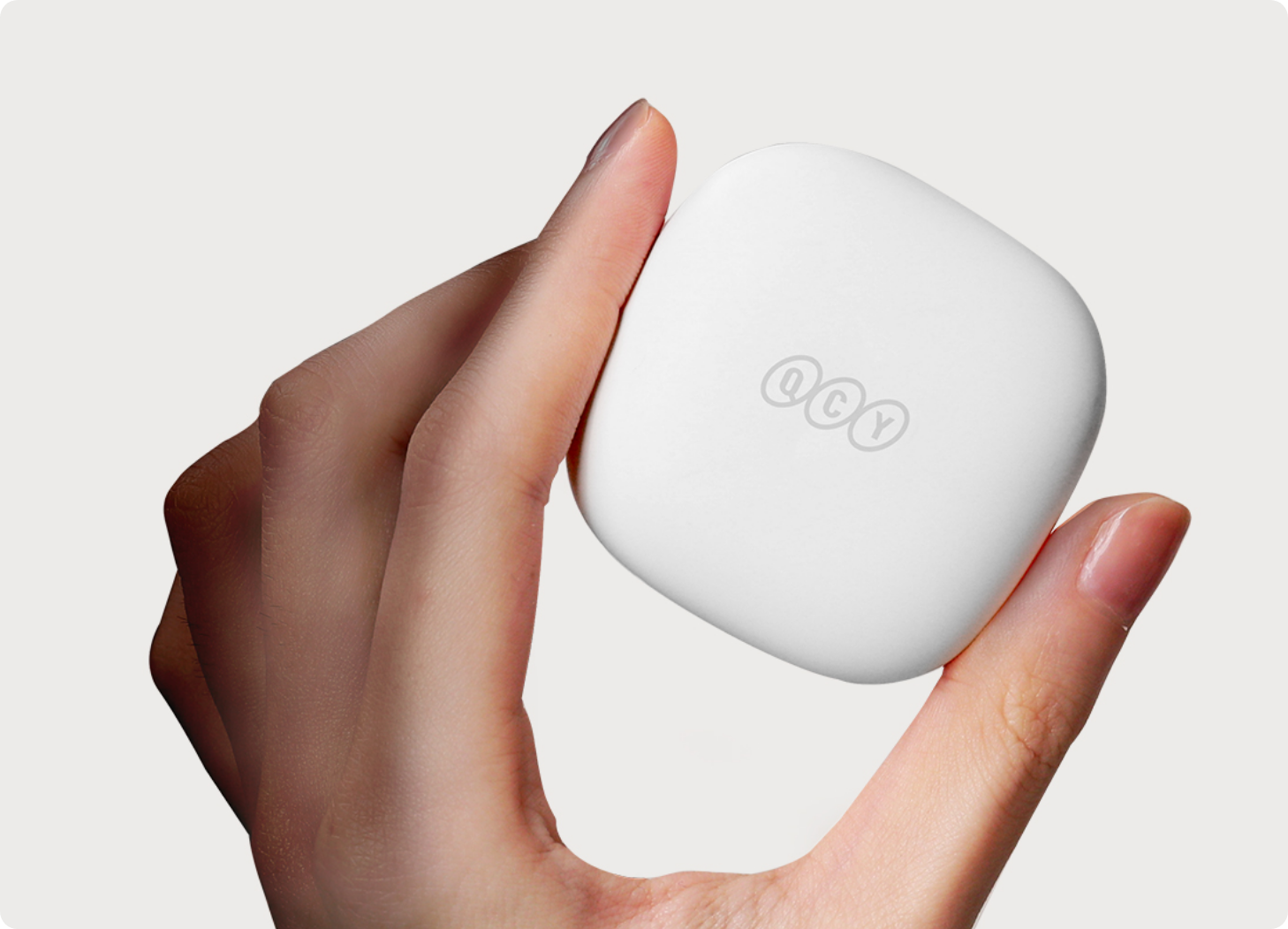 Caja de auriculares QCY blanca en la mano, diseño minimalista con logo, ideal para auriculares inalámbricos.