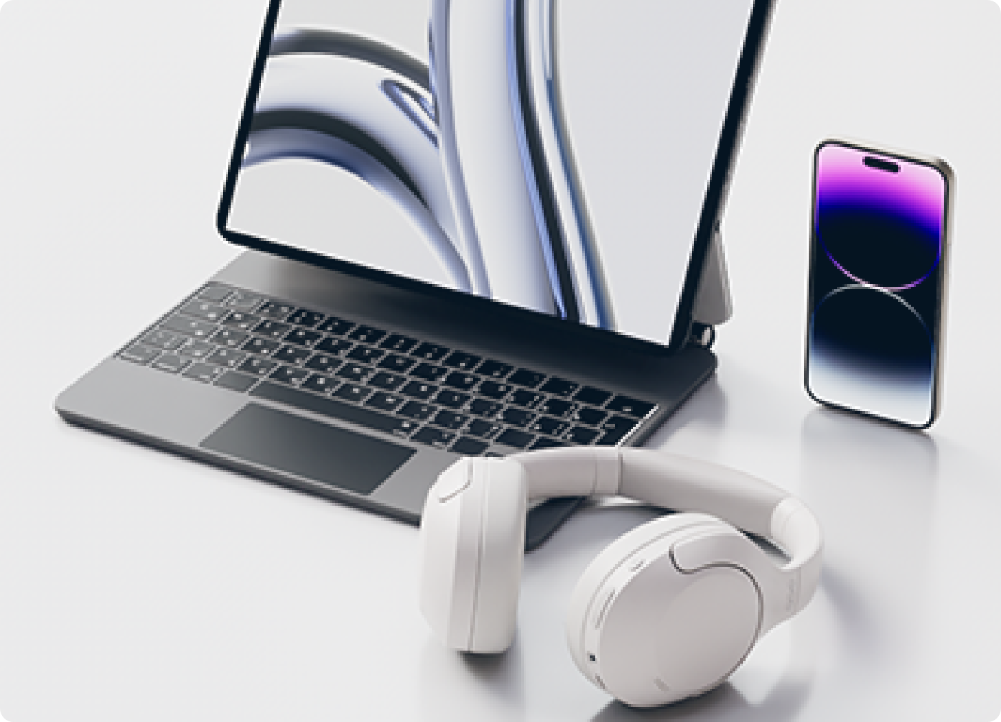 Conjunto moderno de portátil con auriculares blancos y smartphone sobre una mesa clara.