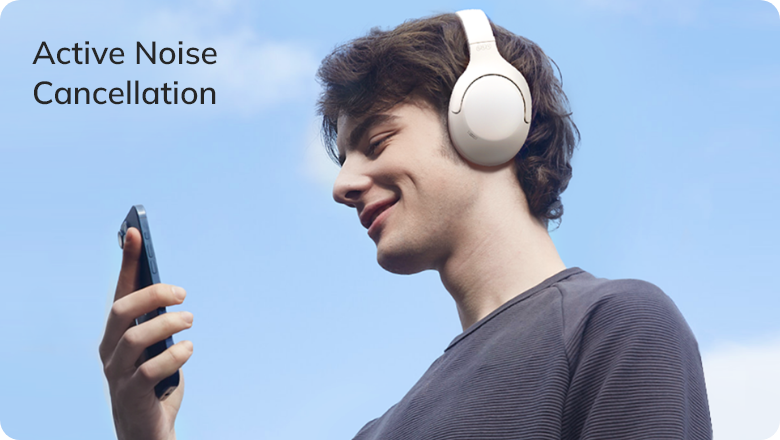 Joven con auriculares ANC blancos, sonriendo mientras escucha música bajo un cielo azul – Cancelación activa de ruido al aire libre erl